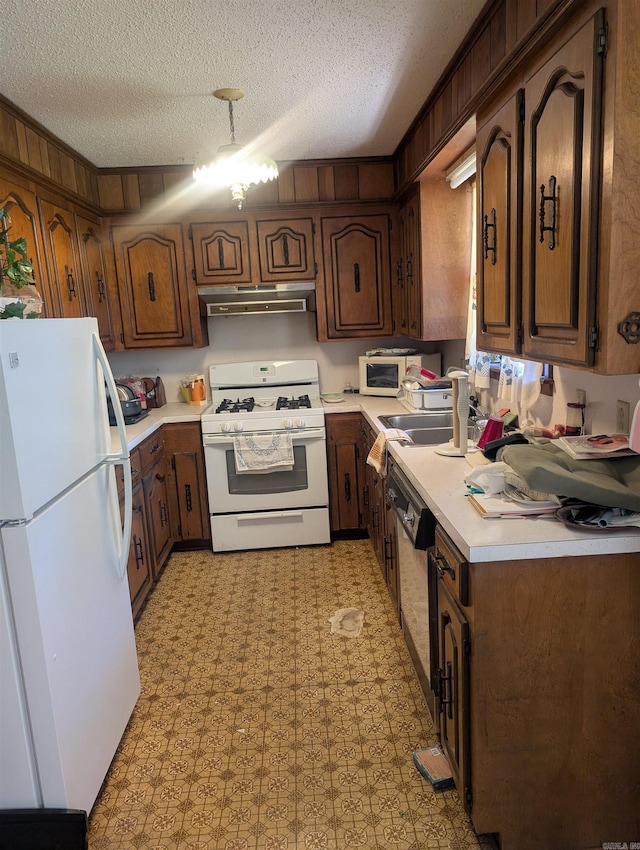kitchen featuring light countertops, a sink, light floors, under cabinet range hood, and white appliances