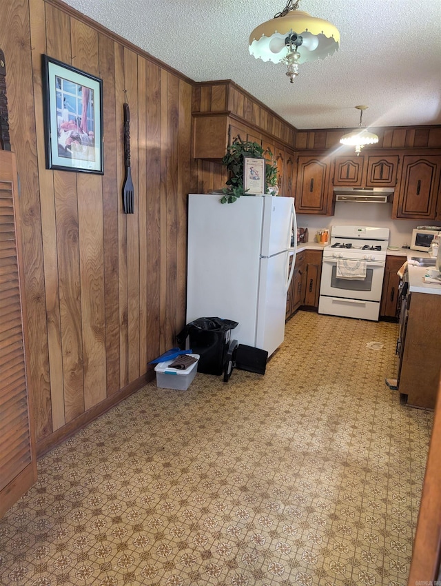 kitchen with light countertops, under cabinet range hood, white appliances, and a textured ceiling