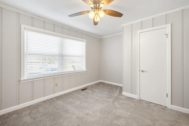 empty room with crown molding, ceiling fan, carpet, and a wealth of natural light
