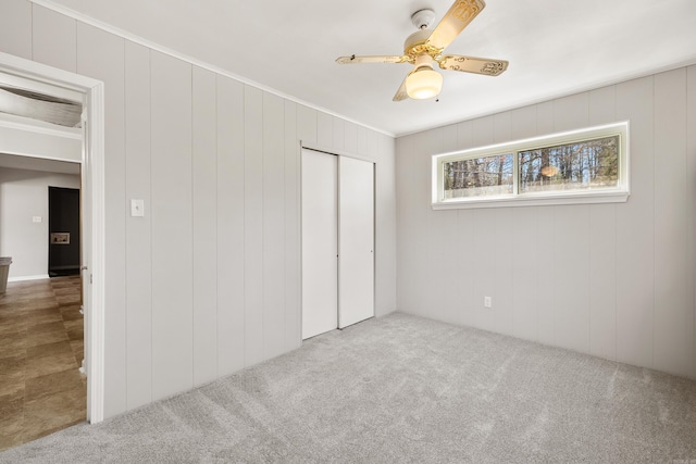 unfurnished bedroom with crown molding, a ceiling fan, carpet, and a closet