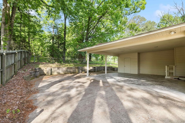 view of patio featuring fence, driveway, and a carport
