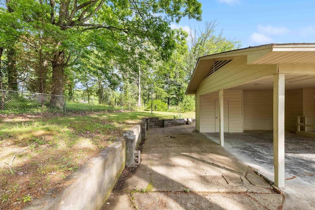 view of side of property with fence, an attached carport, and concrete driveway