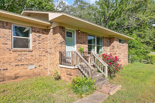 entrance to property with a lawn and brick siding