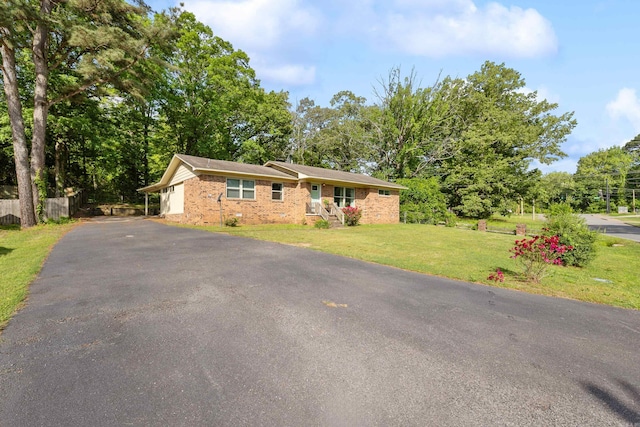 ranch-style home with brick siding, fence, driveway, and a front yard