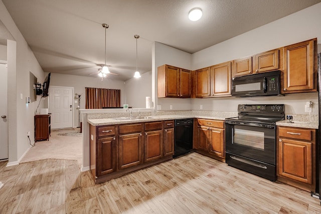 kitchen featuring a sink, light wood-style floors, black appliances, and brown cabinets