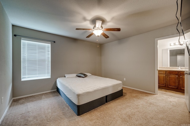 bedroom with connected bathroom, baseboards, light colored carpet, and a sink