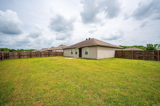 back of property featuring a yard and a fenced backyard