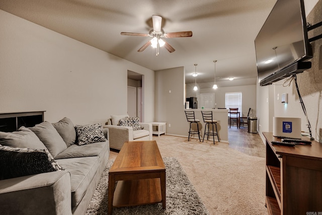 living area featuring ceiling fan, light carpet, and baseboards