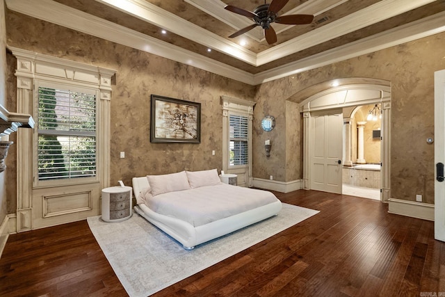 bedroom with ornamental molding, ensuite bathroom, a tray ceiling, and dark wood-style flooring