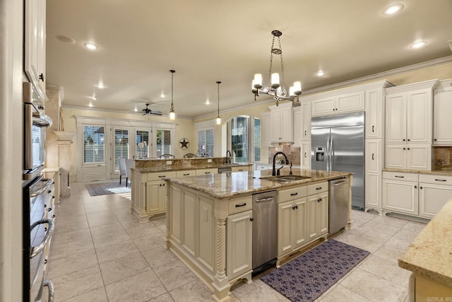 kitchen with crown molding, a center island with sink, a sink, ceiling fan with notable chandelier, and stainless steel appliances