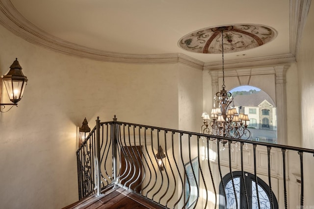 stairs featuring an inviting chandelier, ornamental molding, and wood finished floors