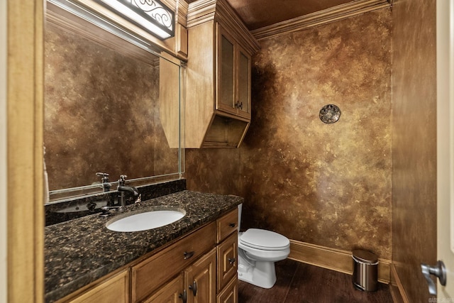 bathroom with vanity, toilet, baseboards, wood finished floors, and ornamental molding