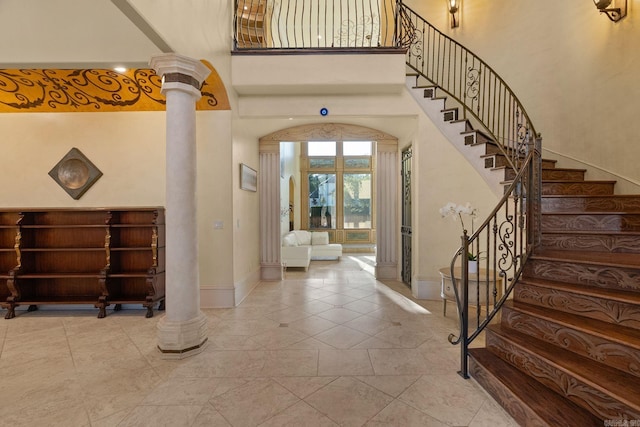 entrance foyer featuring ornate columns, baseboards, a high ceiling, and stairway