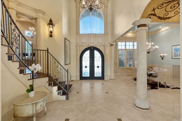 foyer featuring a high ceiling, an inviting chandelier, french doors, stairs, and decorative columns