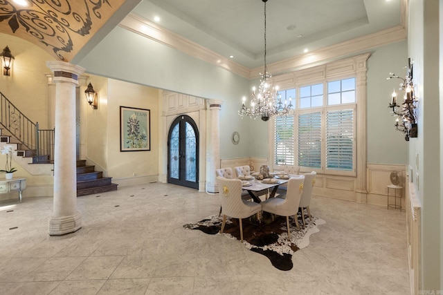 dining area featuring a high ceiling, an inviting chandelier, french doors, stairs, and decorative columns