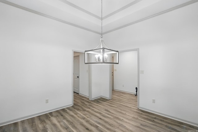 unfurnished dining area featuring baseboards, a towering ceiling, wood finished floors, and a chandelier