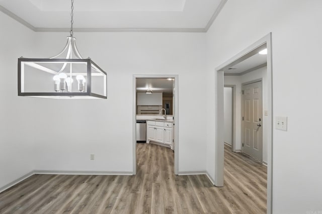 unfurnished dining area with baseboards, ornamental molding, light wood-style flooring, and a notable chandelier