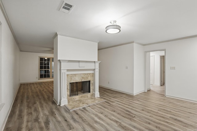 unfurnished living room with visible vents, crown molding, a fireplace, wood finished floors, and baseboards