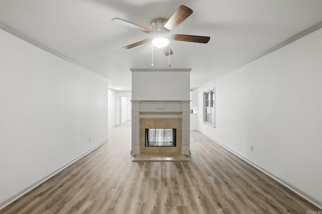 unfurnished living room with baseboards, a fireplace, a ceiling fan, and wood finished floors