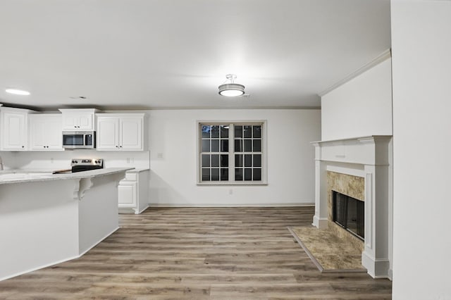 kitchen featuring ornamental molding, light wood finished floors, white cabinets, and stainless steel appliances