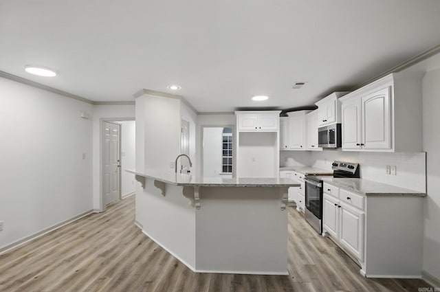 kitchen featuring ornamental molding, light stone countertops, light wood-type flooring, white cabinets, and appliances with stainless steel finishes