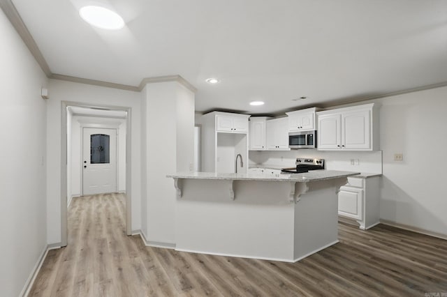 kitchen featuring crown molding, appliances with stainless steel finishes, white cabinets, and light stone counters
