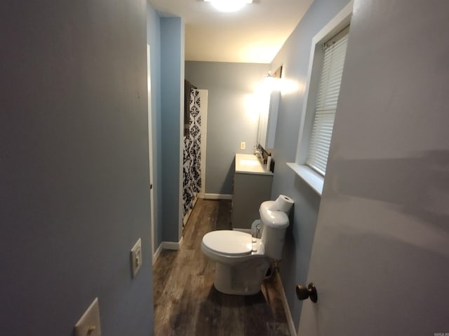 bathroom featuring vanity, toilet, baseboards, curtained shower, and wood finished floors