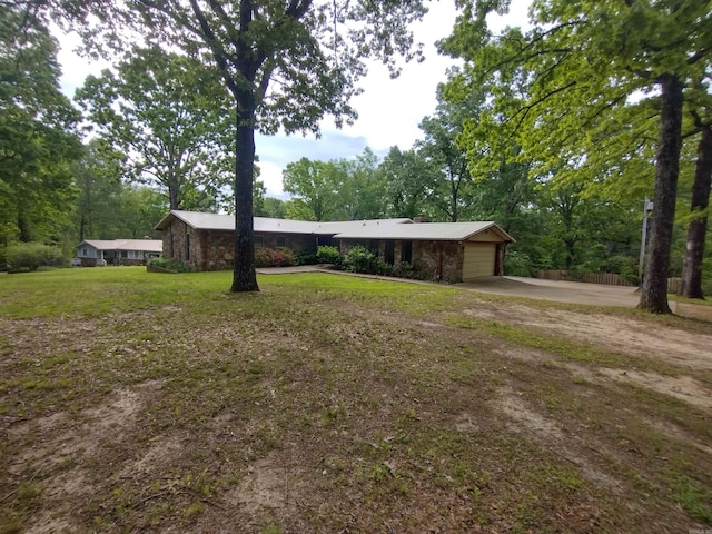 view of front of property with a garage, stone siding, a front yard, and concrete driveway
