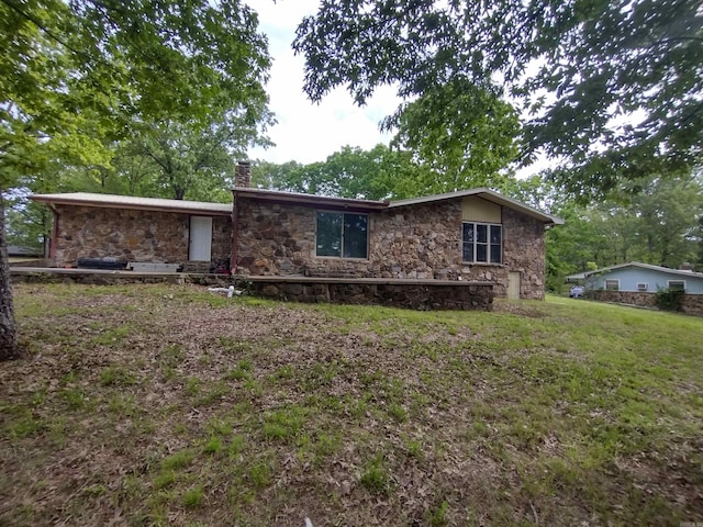 view of front facade with a chimney, a front lawn, and stone siding