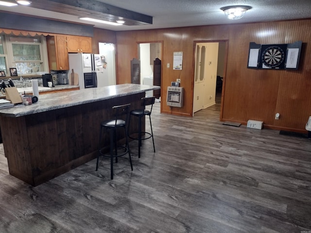 kitchen featuring dark wood-style flooring, a breakfast bar, light countertops, white fridge with ice dispenser, and heating unit