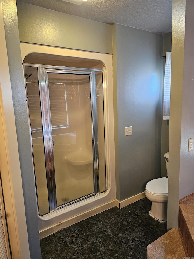 161 Funderburg Rd, Mineral Sprs, AR 71851 - bathroom featuring baseboards, a stall shower, toilet, and a textured ceiling