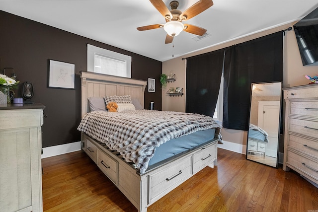 bedroom with baseboards, ceiling fan, wood finished floors, and visible vents