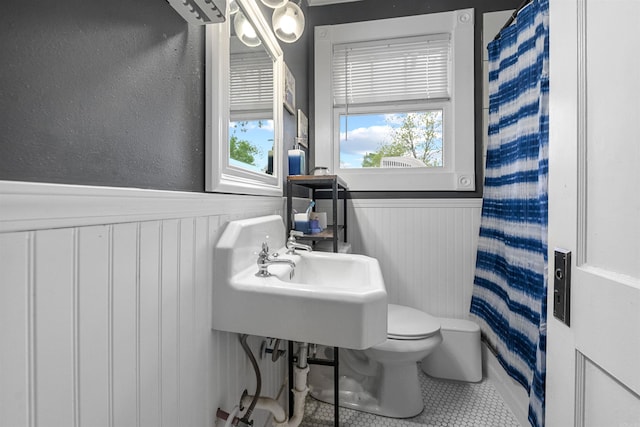 full bath with a wainscoted wall, tile patterned flooring, toilet, and curtained shower