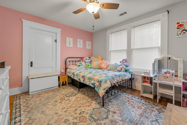 bedroom with visible vents, a ceiling fan, baseboards, and wood finished floors
