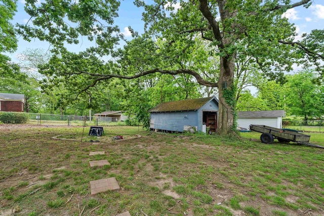 view of yard featuring a shed, an outbuilding, and fence