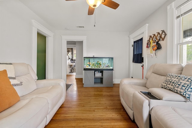 living area featuring light wood-style floors, baseboards, ceiling fan, and visible vents