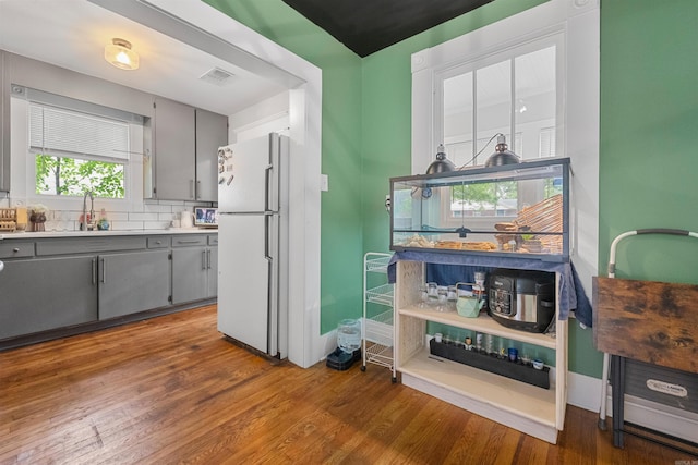 kitchen with a sink, gray cabinets, freestanding refrigerator, and visible vents
