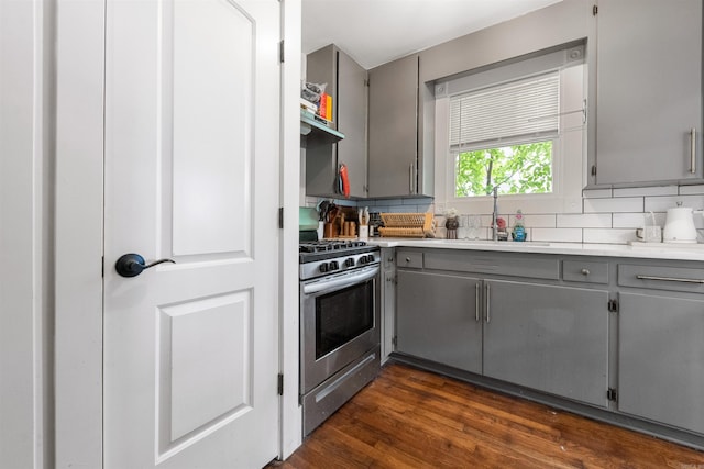 kitchen featuring backsplash, gas range, gray cabinetry, light countertops, and a sink