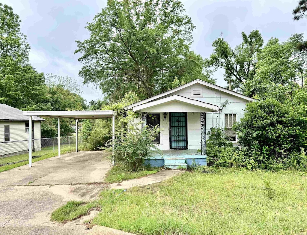 bungalow-style house with covered porch, fence, and driveway