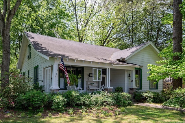 ranch-style home featuring roof with shingles and covered porch