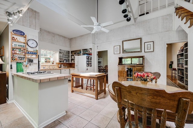 kitchen featuring a ceiling fan, stainless steel gas cooktop, light tile patterned floors, and white fridge with ice dispenser