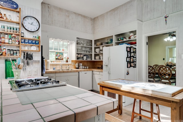 kitchen featuring tile countertops, open shelves, a sink, white cabinets, and white fridge with ice dispenser