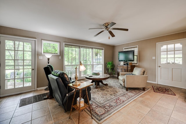 living area with ceiling fan, ornamental molding, a wealth of natural light, and tile patterned flooring