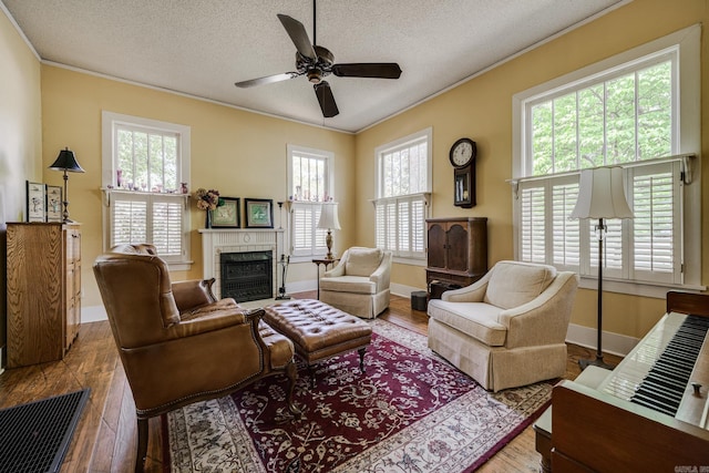 living area with crown molding, a fireplace with flush hearth, wood finished floors, and a wealth of natural light