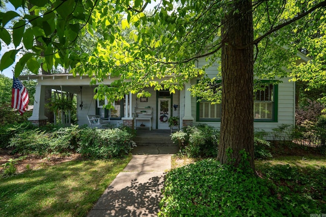 view of property hidden behind natural elements with covered porch