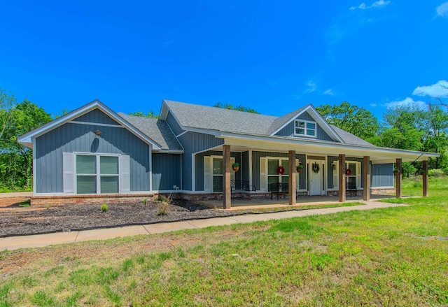 country-style home with a shingled roof, covered porch, and a front yard