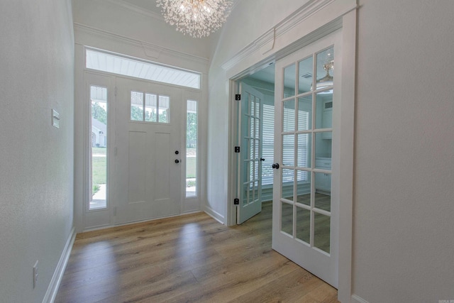 foyer entrance with an inviting chandelier, a textured wall, wood finished floors, baseboards, and french doors