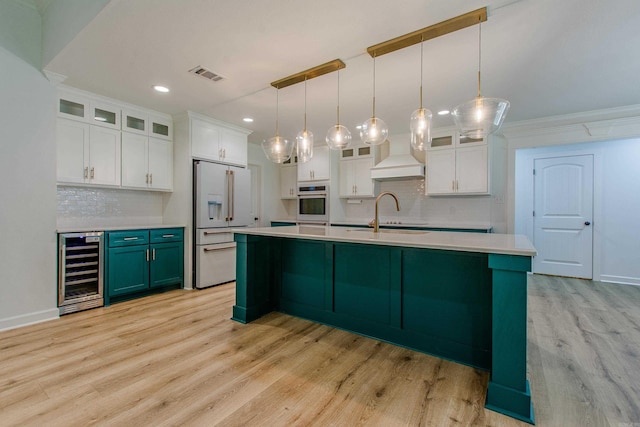kitchen featuring oven, high end white fridge, light countertops, wine cooler, and visible vents