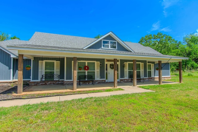 back of property with board and batten siding, a lawn, a shingled roof, and a porch