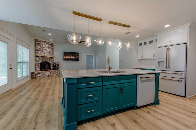 kitchen with dishwasher, high end white fridge, a sink, white cabinets, and light wood finished floors
